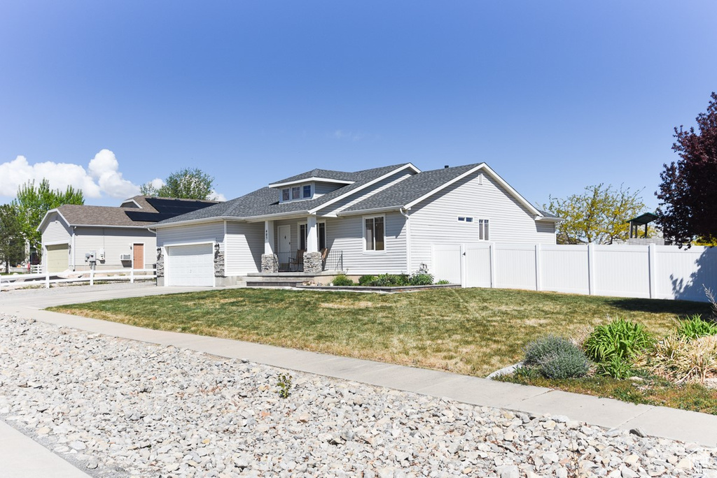 View of front of property with fence, roof with shingles, an attached garage, a front yard, and driveway