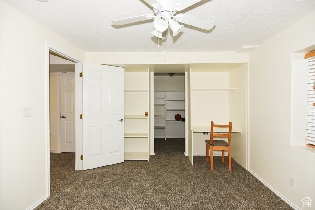 Bedroom featuring a ceiling fan, a spacious closet, dark carpet, and a closet