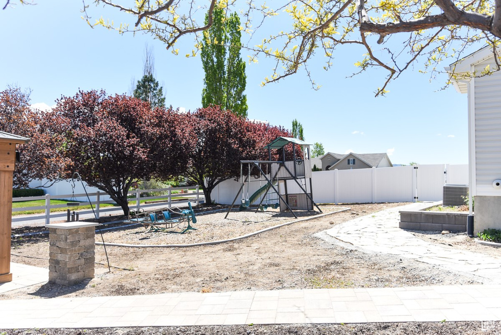 View of yard with a playground, fence, and cooling unit
