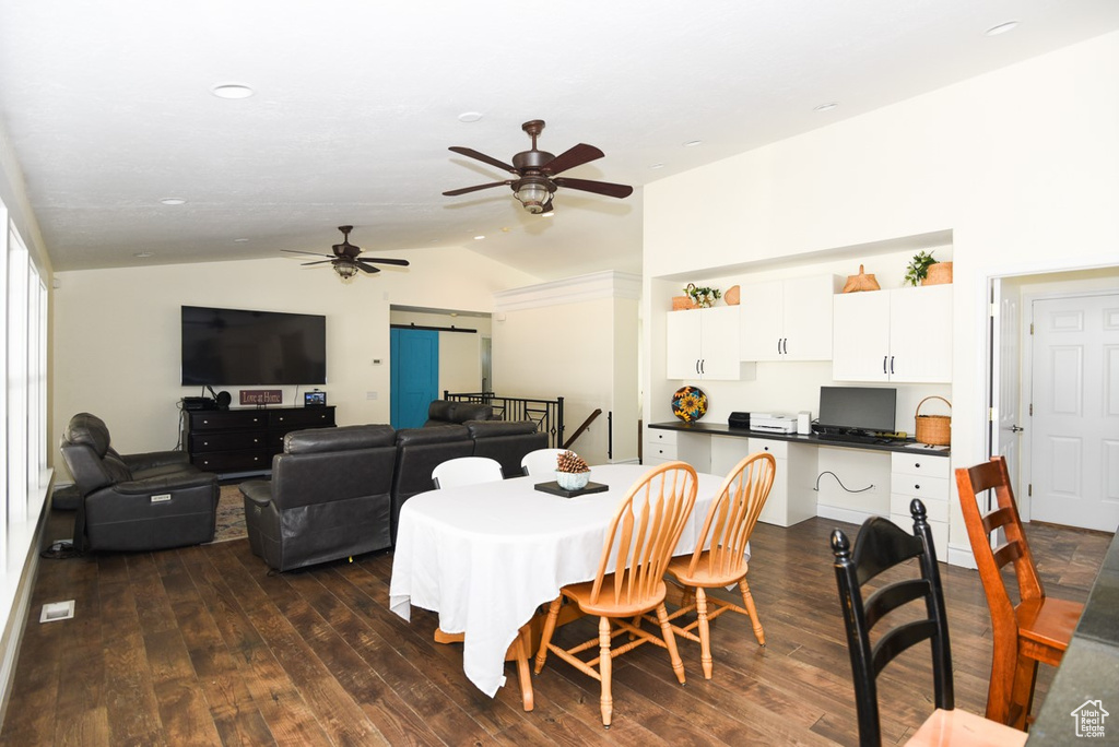 Dining space featuring dark wood-style flooring, ceiling fan, and lofted ceiling