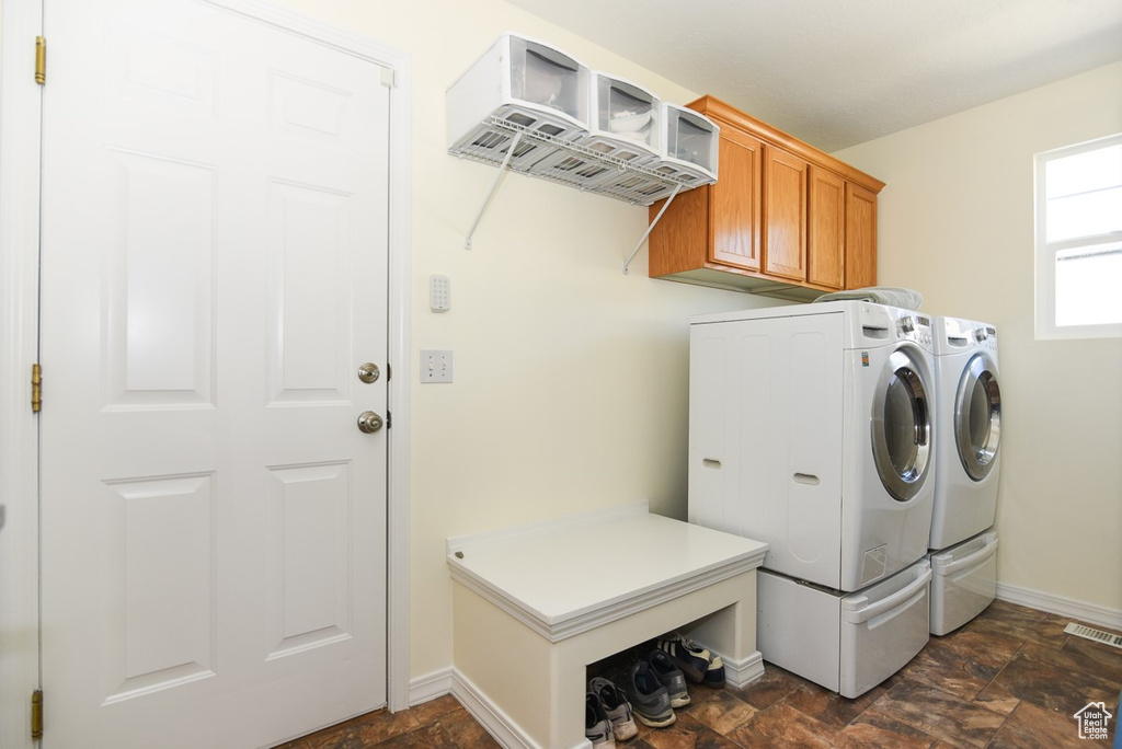 Laundry room with washing machine and clothes dryer, cabinet space, baseboards, stone finish flooring, and visible vents