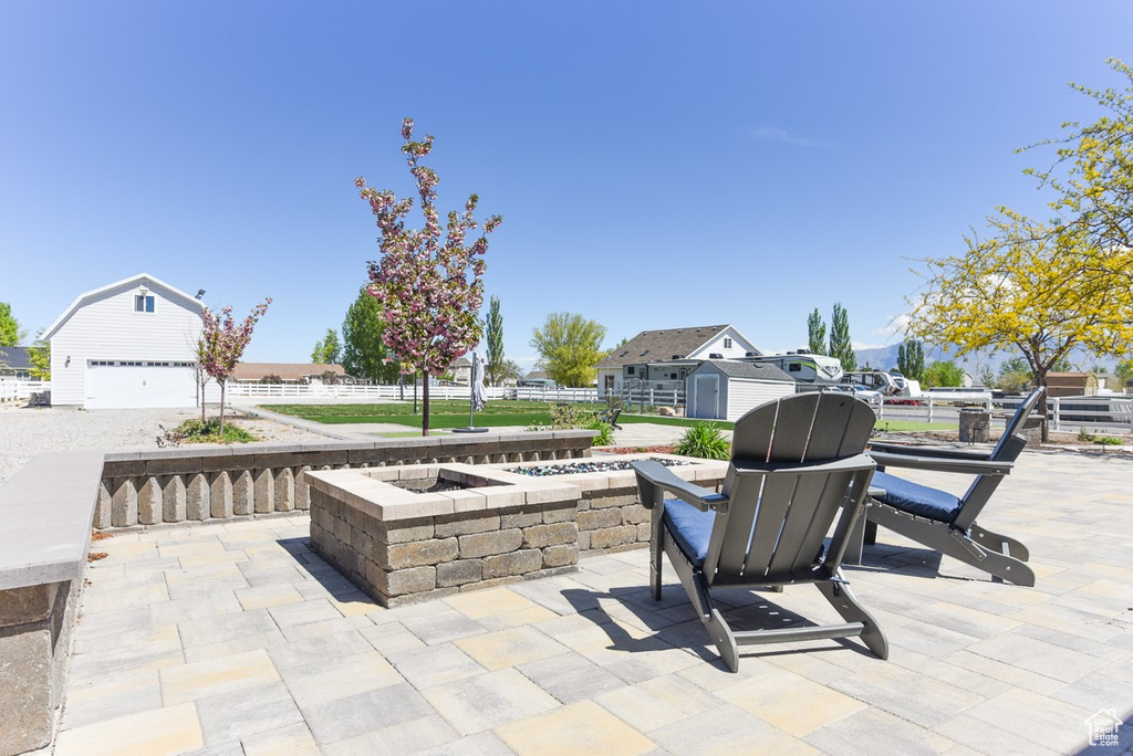 View of patio featuring a garage, a fire pit, and an outbuilding