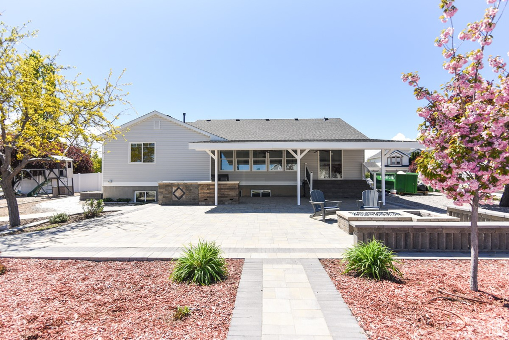 Back of property featuring fence, an outdoor fire pit, and a patio area