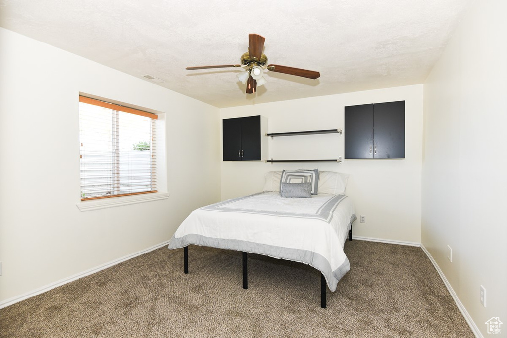 Carpeted bedroom with baseboards, ceiling fan, and visible vents
