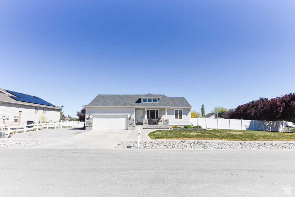 View of front of property featuring fence, an attached garage, driveway, and a front yard