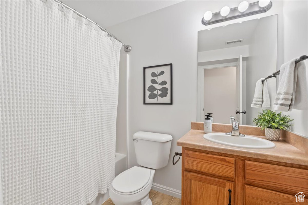 Bathroom featuring tile patterned flooring, vanity, toilet, shower / bathtub combination with curtain, and visible vents