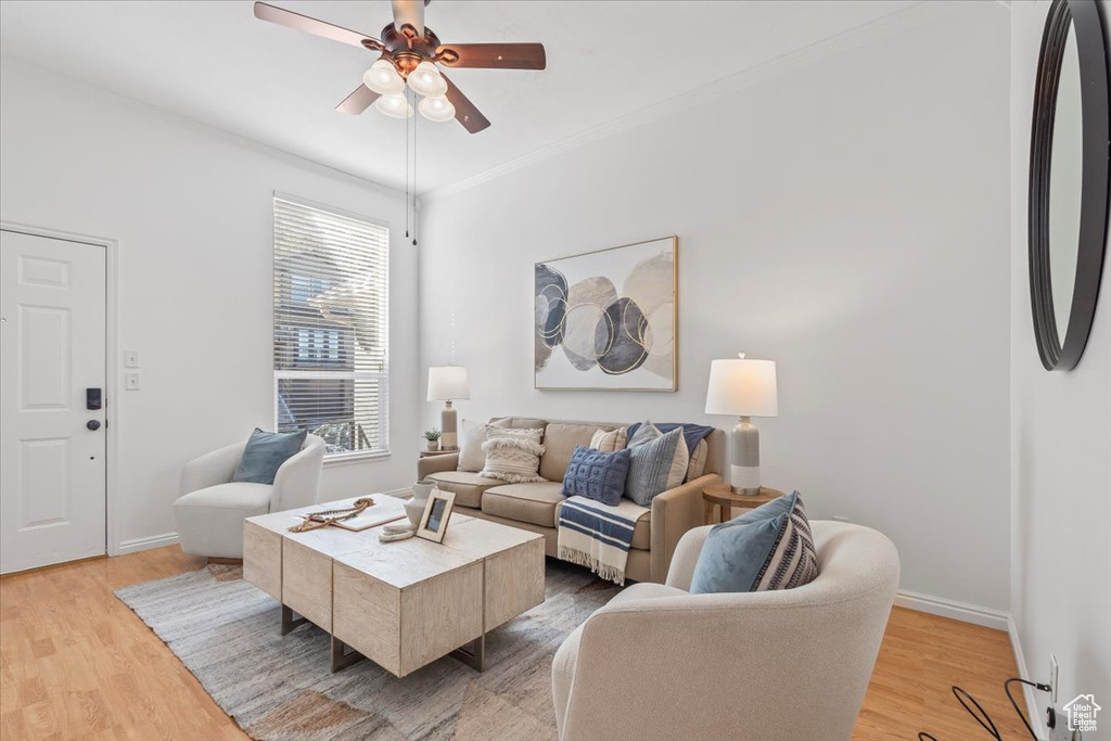 Living room featuring light wood-style floors, ornamental molding, baseboards, and ceiling fan