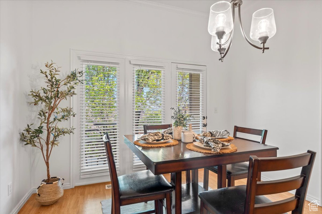 Dining space featuring light wood-style floors, crown molding, baseboards, and plenty of natural light