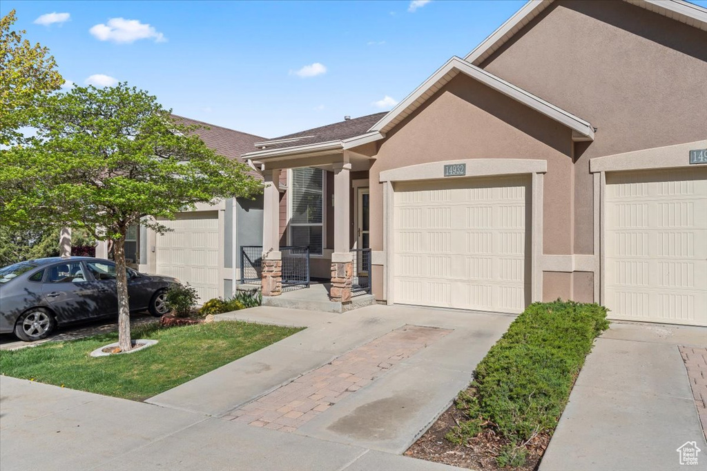 View of front of home featuring stucco siding, an attached garage, and driveway