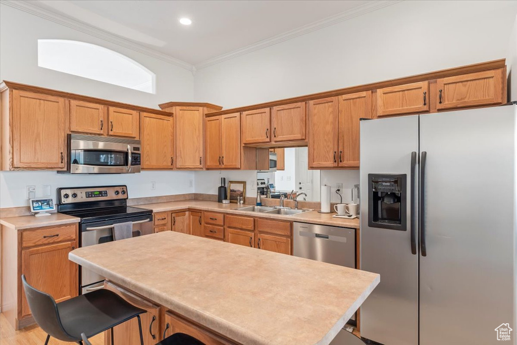 Kitchen featuring crown molding, a center island, light countertops, a breakfast bar, and stainless steel appliances