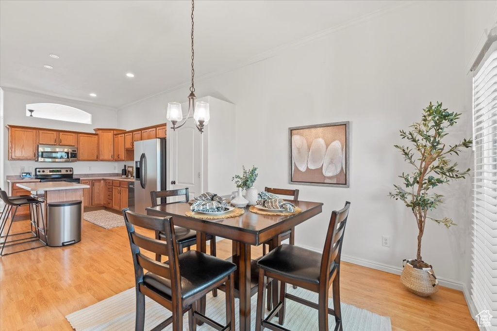 Dining area with ornamental molding, baseboards, recessed lighting, light wood-style flooring, and a notable chandelier