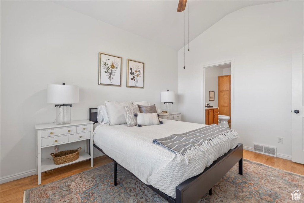 Bedroom featuring visible vents, wood finished floors, baseboards, lofted ceiling, and ensuite bathroom