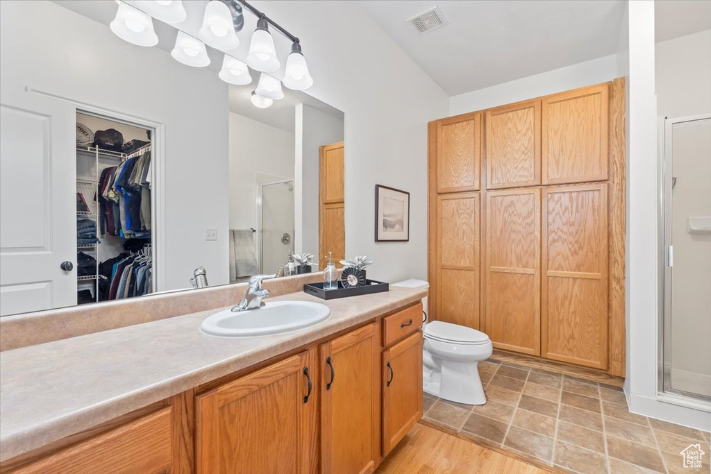 Bathroom with vanity, toilet, a shower stall, a spacious closet, and visible vents