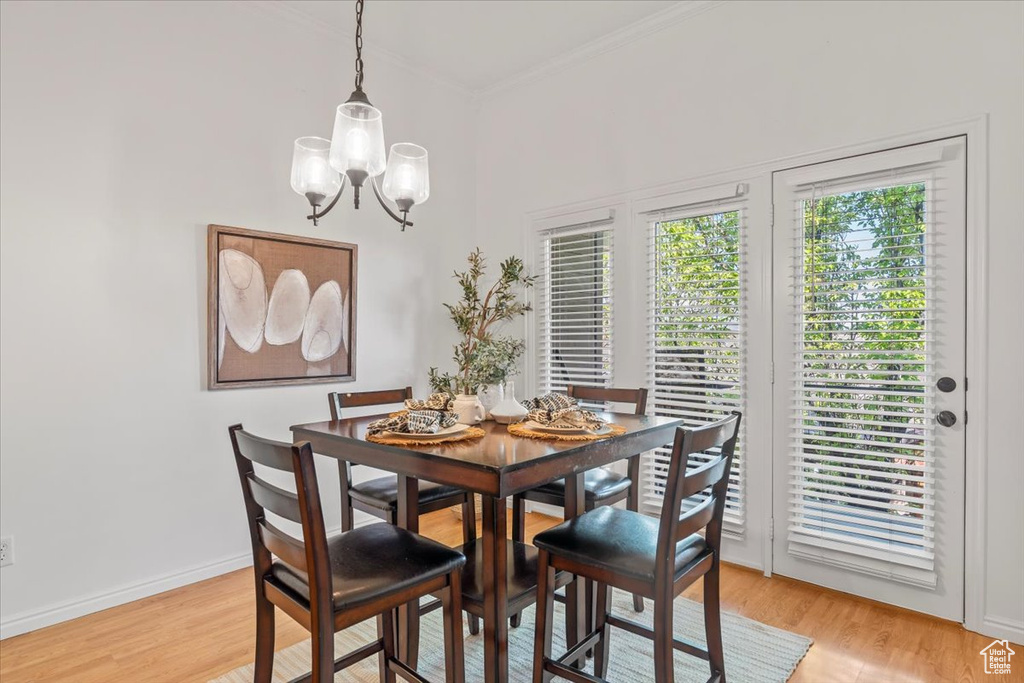 Dining room with crown molding, baseboards, a notable chandelier, and light wood-style floors