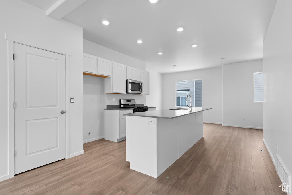 Kitchen featuring visible vents, a sink, light wood-style floors, stainless steel appliances, and white cabinetry