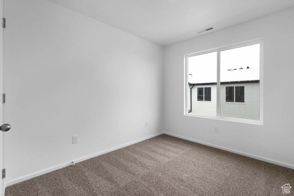 Spare room with visible vents, carpet flooring, and baseboards