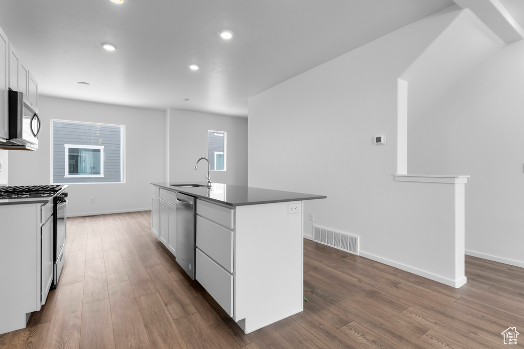 Kitchen featuring dark wood-style floors, stainless steel appliances, visible vents, and white cabinetry