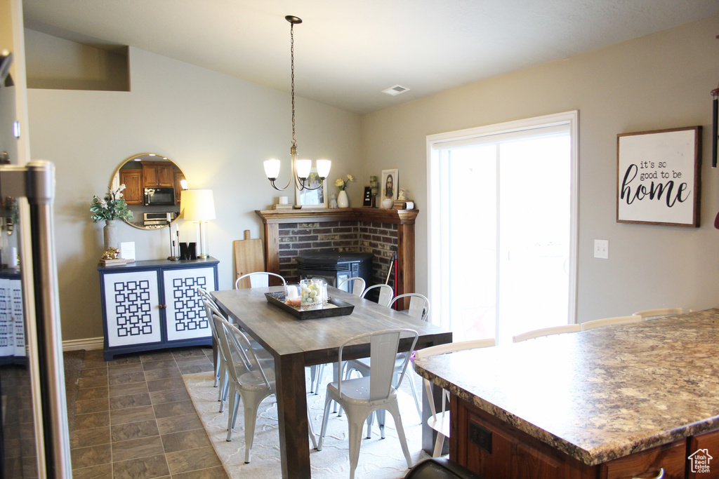 Dining space featuring a fireplace, a chandelier, and dark tile floors