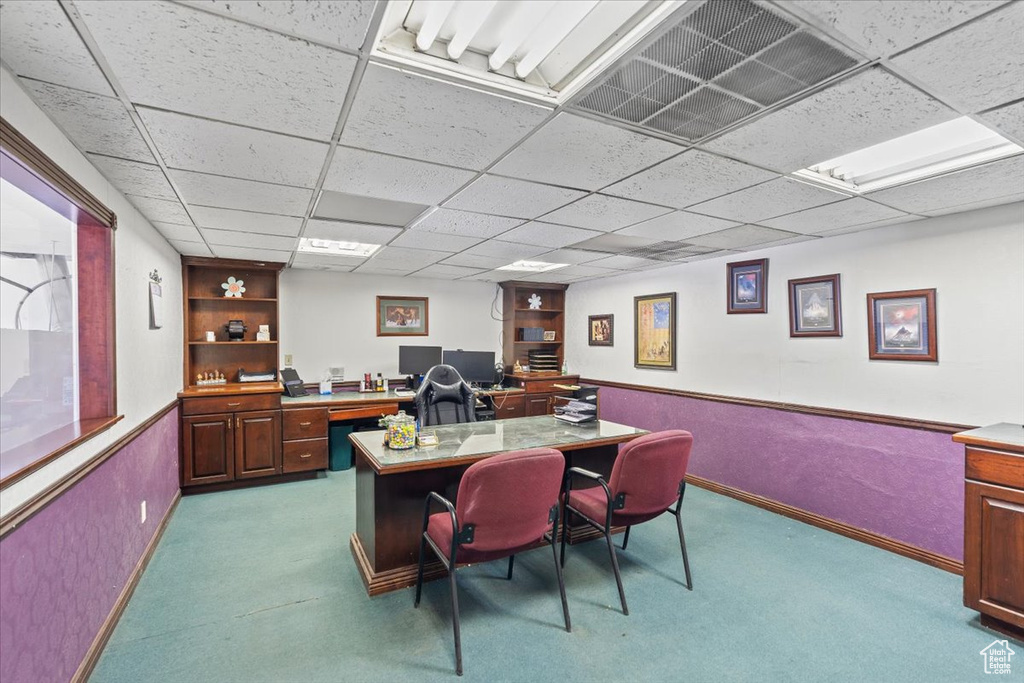 Carpeted office space with visible vents, a paneled ceiling, and baseboards