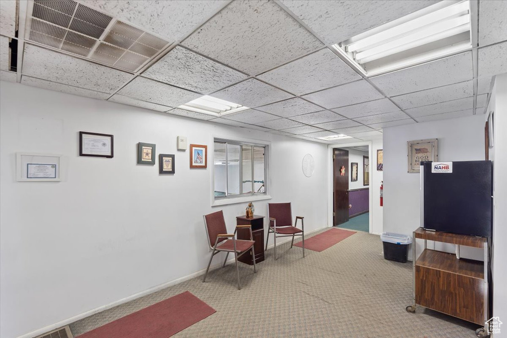 Interior space with carpet floors, visible vents, baseboards, and a paneled ceiling