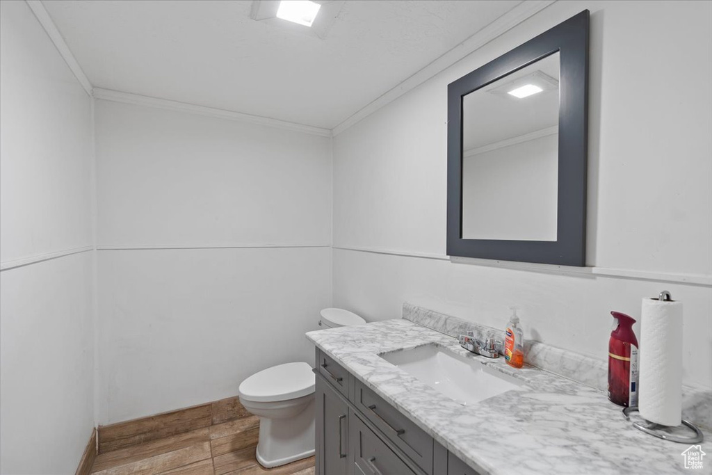 Bathroom with crown molding, wood finished floors, toilet, and vanity