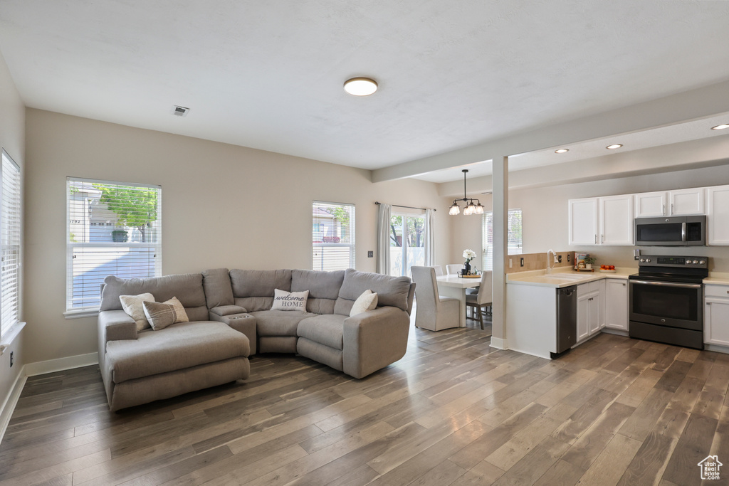 Living area with recessed lighting, an inviting chandelier, a healthy amount of sunlight, and wood finished floors