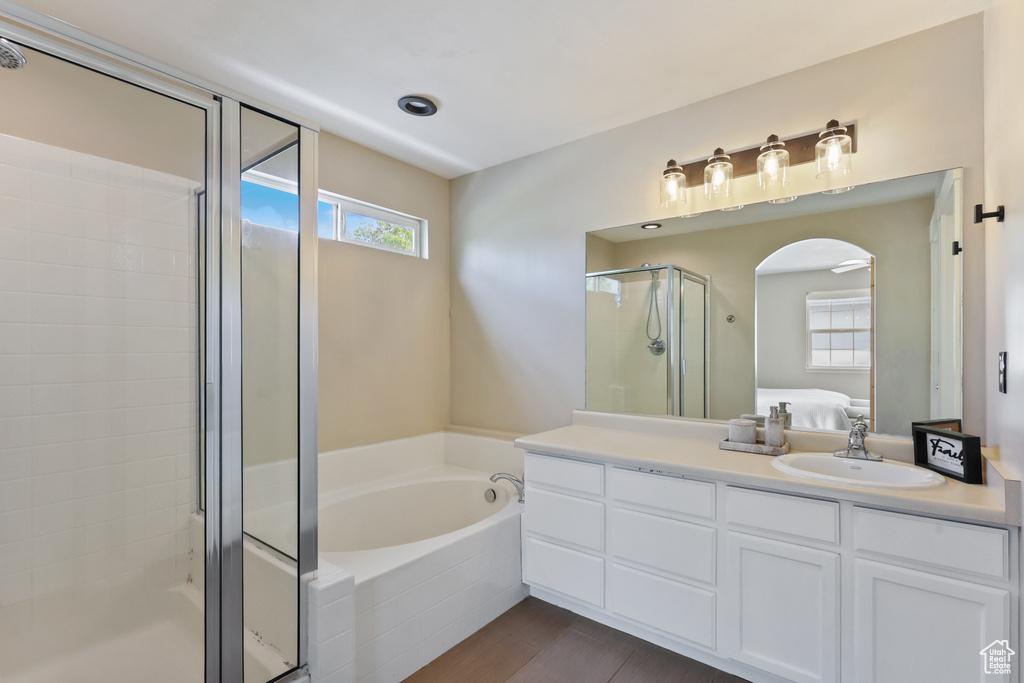 Ensuite bathroom featuring a garden tub, vanity, wood finished floors, ensuite bathroom, and a stall shower