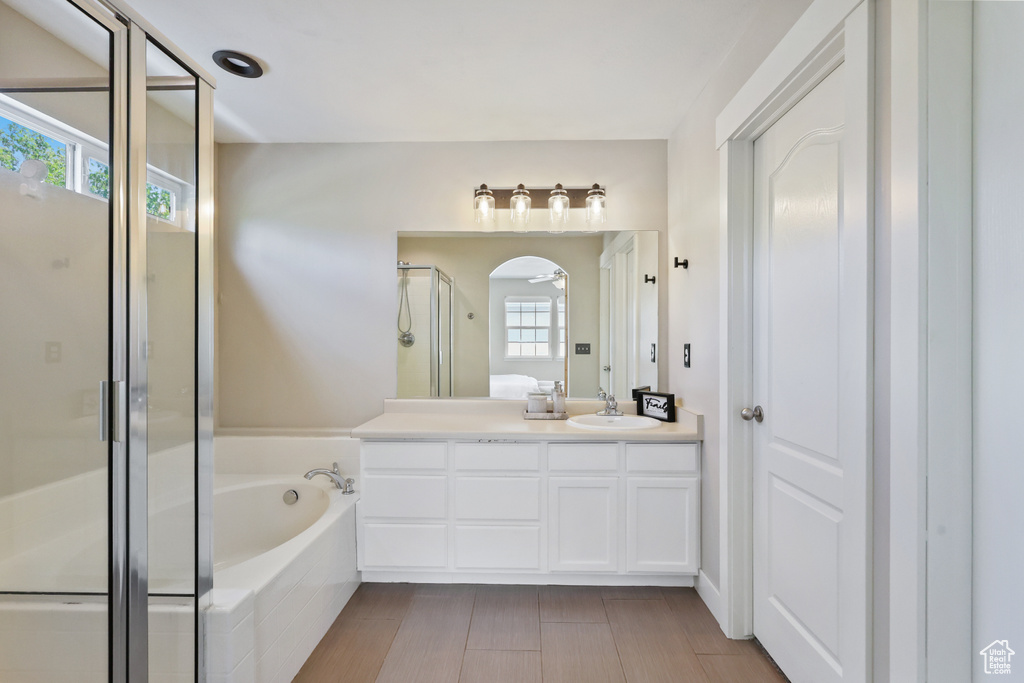 Full bath with a sink, double vanity, a stall shower, and a garden tub
