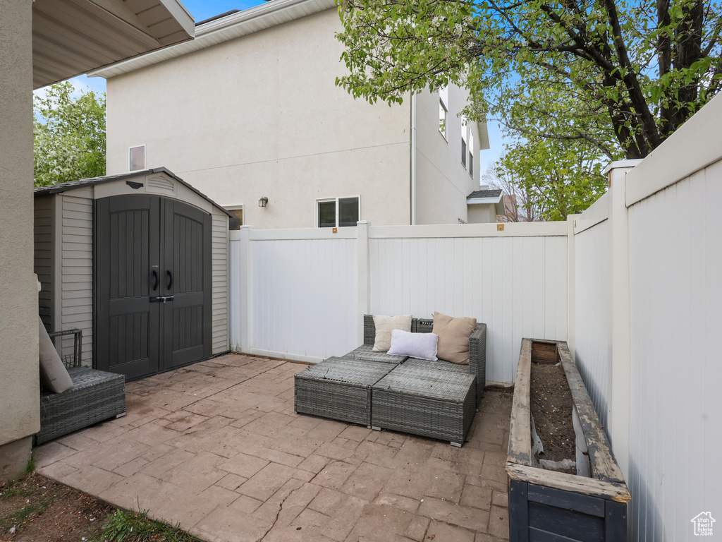 View of patio with a fenced backyard, a storage unit, and an outdoor structure