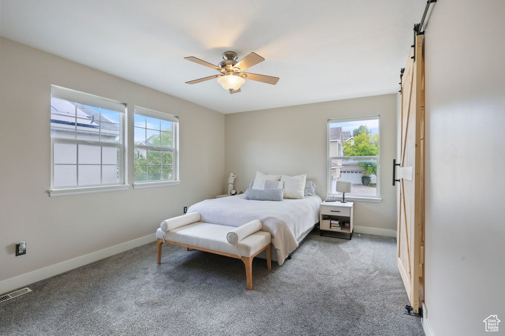 Bedroom with baseboards, visible vents, a barn door, and carpet