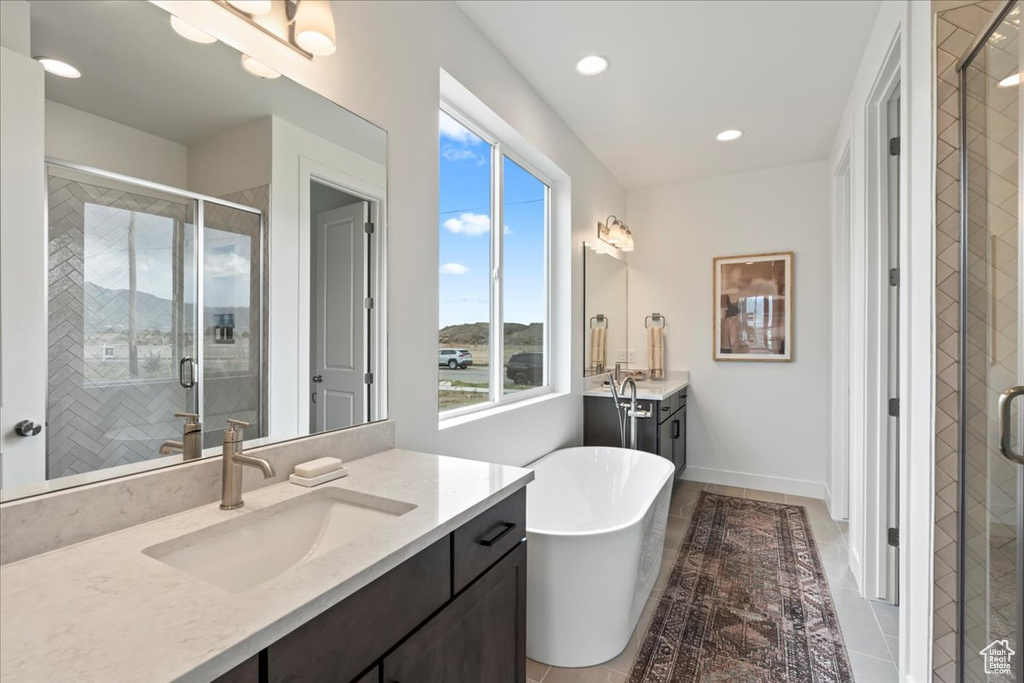 Bathroom with a freestanding tub, a shower stall, two vanities, a sink, and tile patterned floors