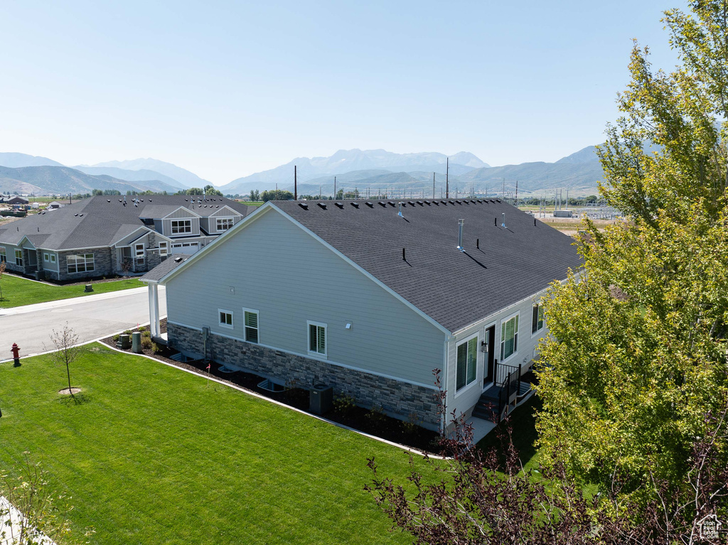 Exterior space with a lawn, a shingled roof, a mountain view, and stone siding