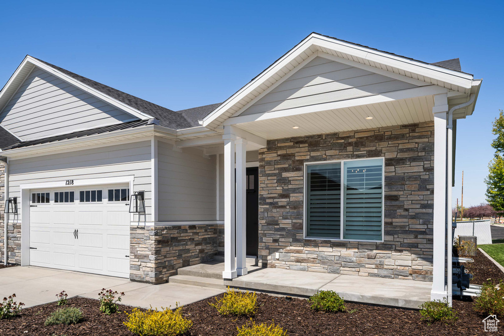 Craftsman inspired home with an attached garage, concrete driveway, and stone siding
