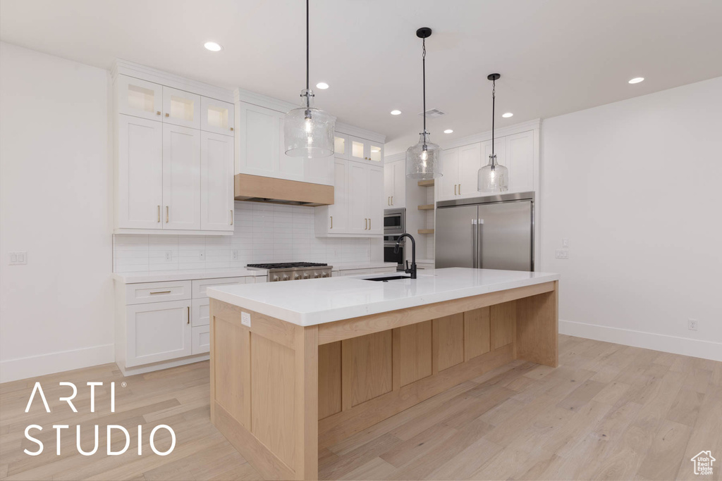 Kitchen featuring built in appliances, backsplash, baseboards, a sink, and white cabinetry