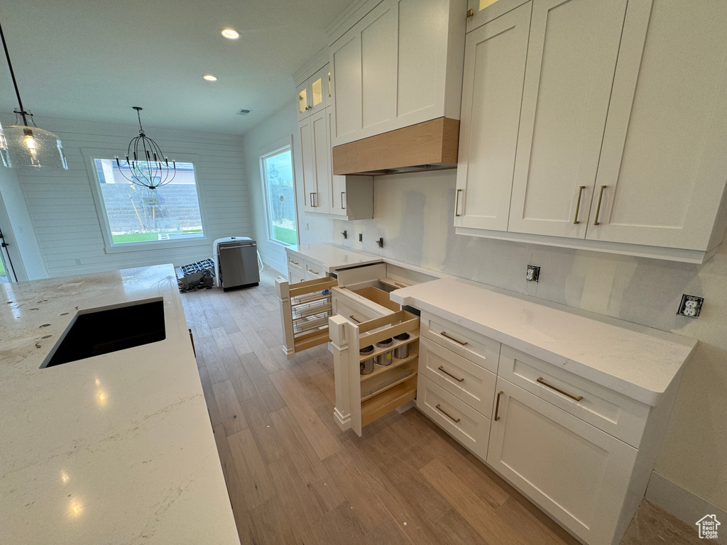 Kitchen with light stone countertops, light wood-style floors, recessed lighting, white cabinets, and a sink