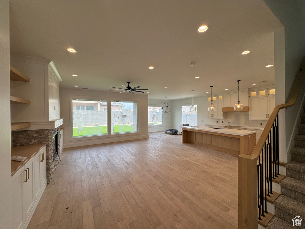 Kitchen featuring open shelves, light wood-style floors, recessed lighting, white cabinets, and ceiling fan with notable chandelier