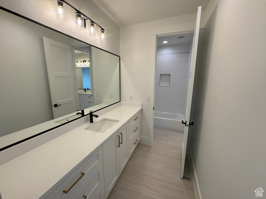 Bathroom with vanity, baseboards, and shower / tub combination