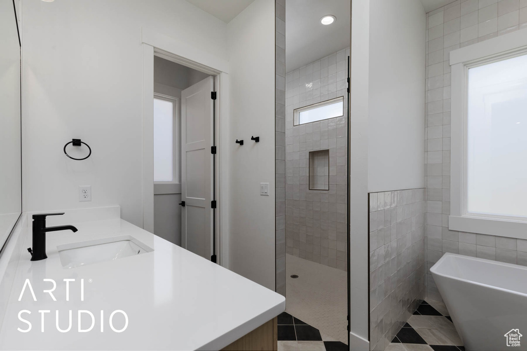 Bathroom with plenty of natural light, a soaking tub, a walk in shower, double vanity, and recessed lighting