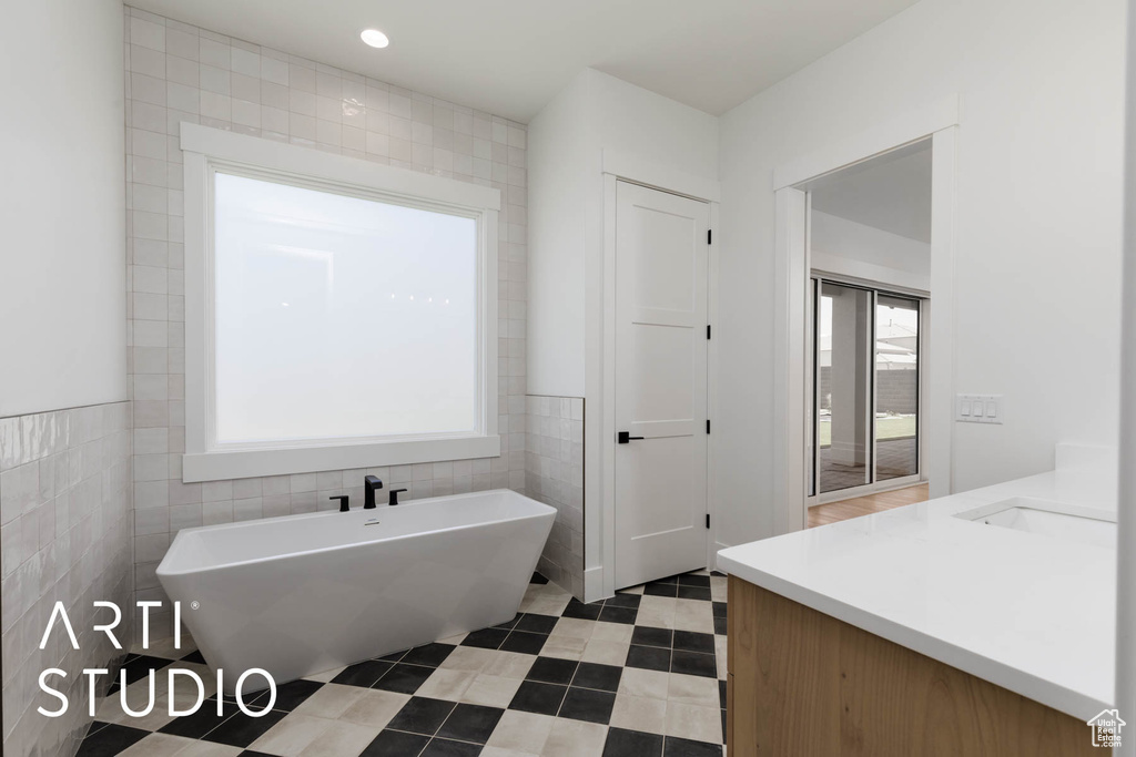 Bathroom with tile walls, a freestanding bath, and vanity