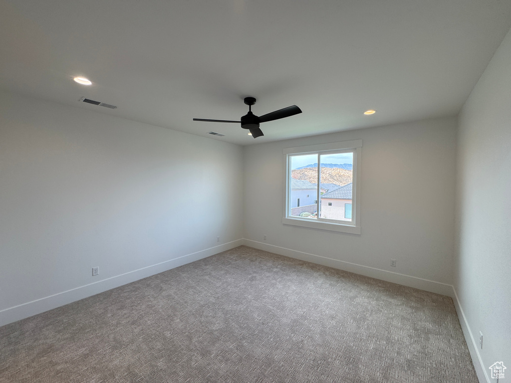 Unfurnished room with a ceiling fan, baseboards, visible vents, and light carpet