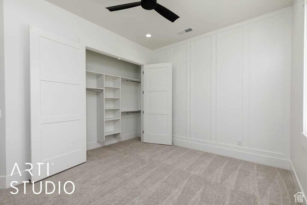 Unfurnished bedroom with light carpet, a decorative wall, recessed lighting, a closet, and a ceiling fan