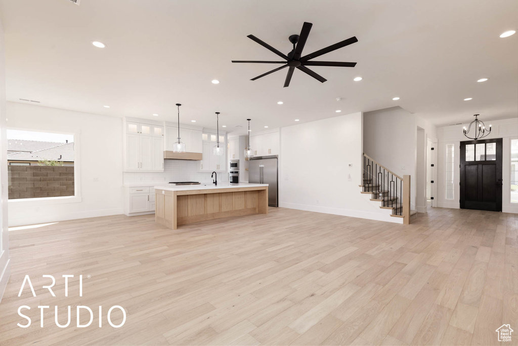 Kitchen featuring high quality fridge, open floor plan, light countertops, a sink, and a kitchen island with sink