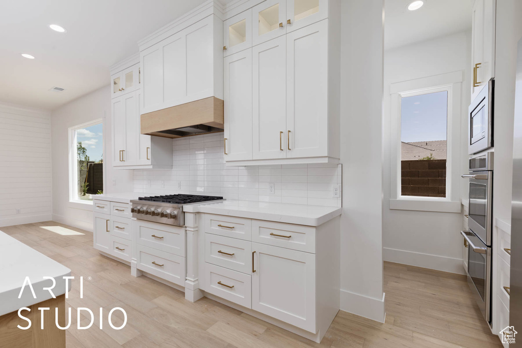 Kitchen with appliances with stainless steel finishes, baseboards, backsplash, white cabinets, and recessed lighting