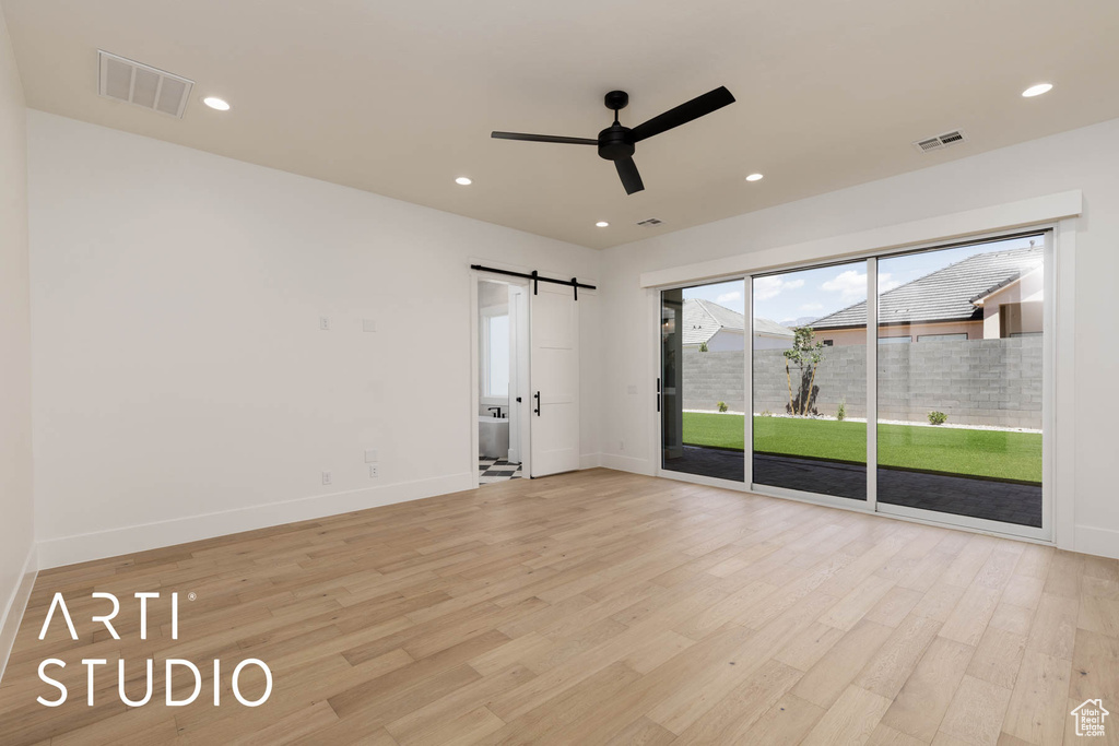 Spare room featuring a barn door, a ceiling fan, light wood-type flooring, baseboards, and recessed lighting