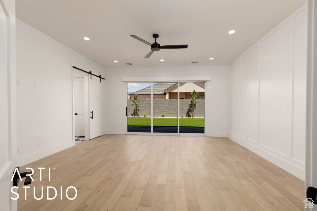 Unfurnished bedroom featuring a barn door, access to exterior, light wood-style floors, baseboards, and recessed lighting