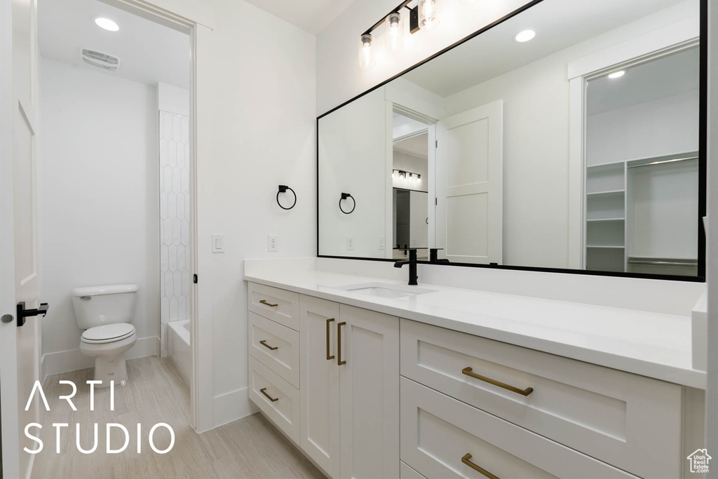 Bathroom with toilet, vanity, baseboards, shower / bath combo with shower curtain, and recessed lighting
