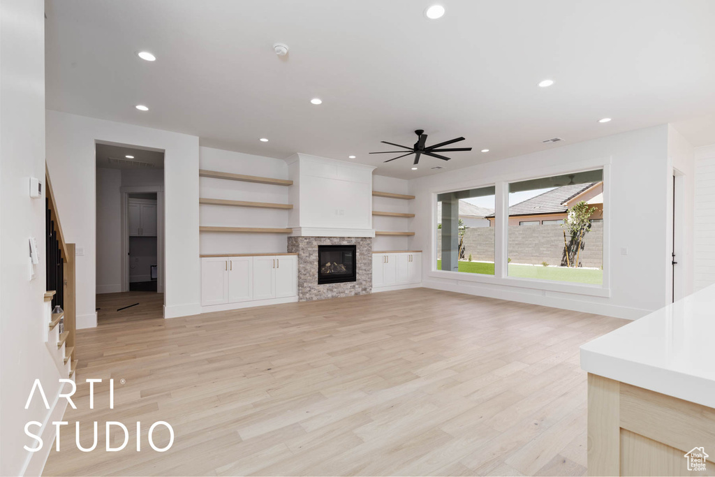 Unfurnished living room featuring ceiling fan, light wood finished floors, recessed lighting, a glass covered fireplace, and baseboards