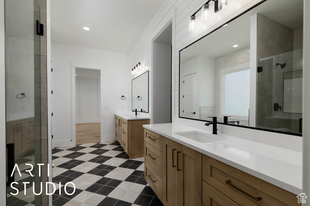 Bathroom featuring a shower stall, two vanities, and baseboards