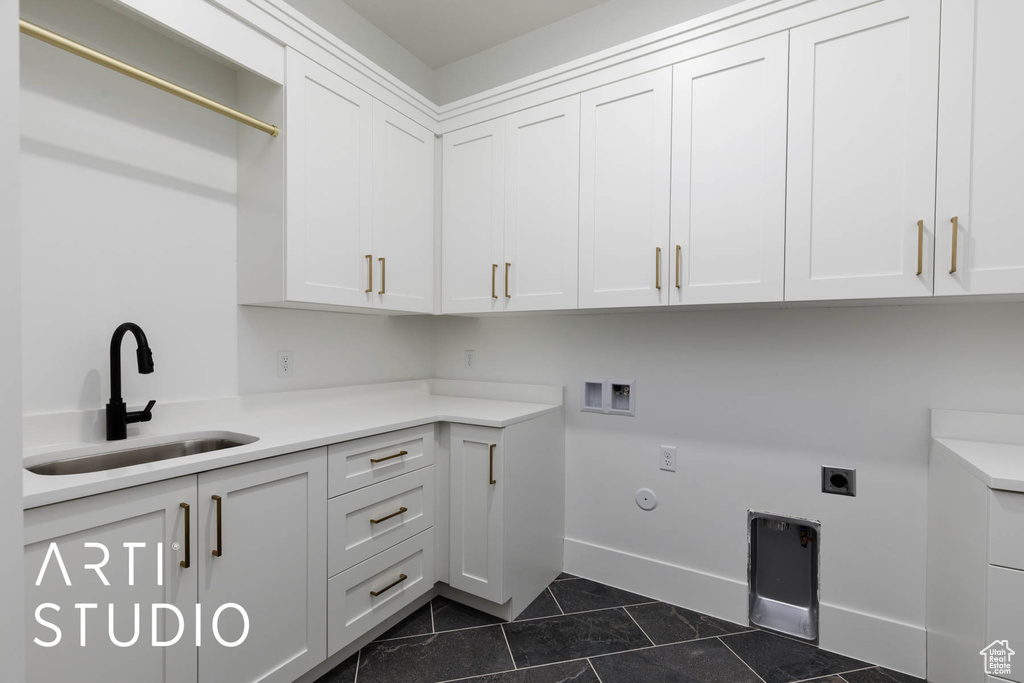 Washroom featuring cabinet space, dark tile patterned flooring, electric dryer hookup, baseboards, and washer hookup