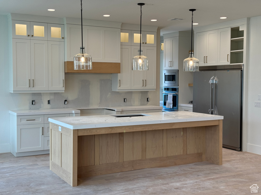 Kitchen with light wood-style floors, a kitchen island, stainless steel appliances, and recessed lighting